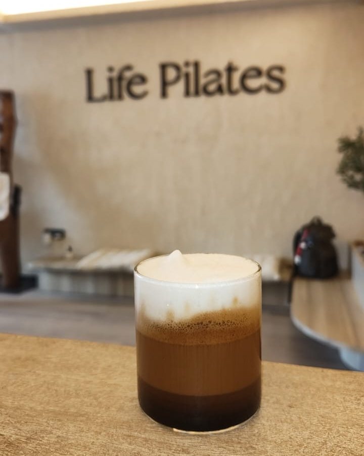 A layered coffee on the counter, with the Life Pilates wall behind it