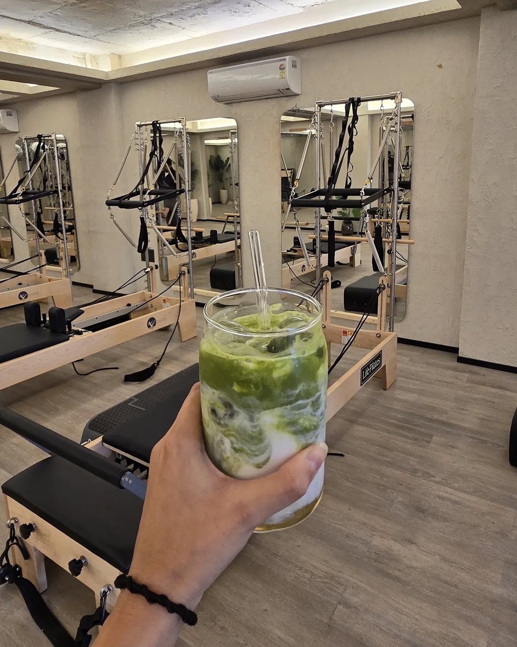An iced matcha held up in the reformer studio