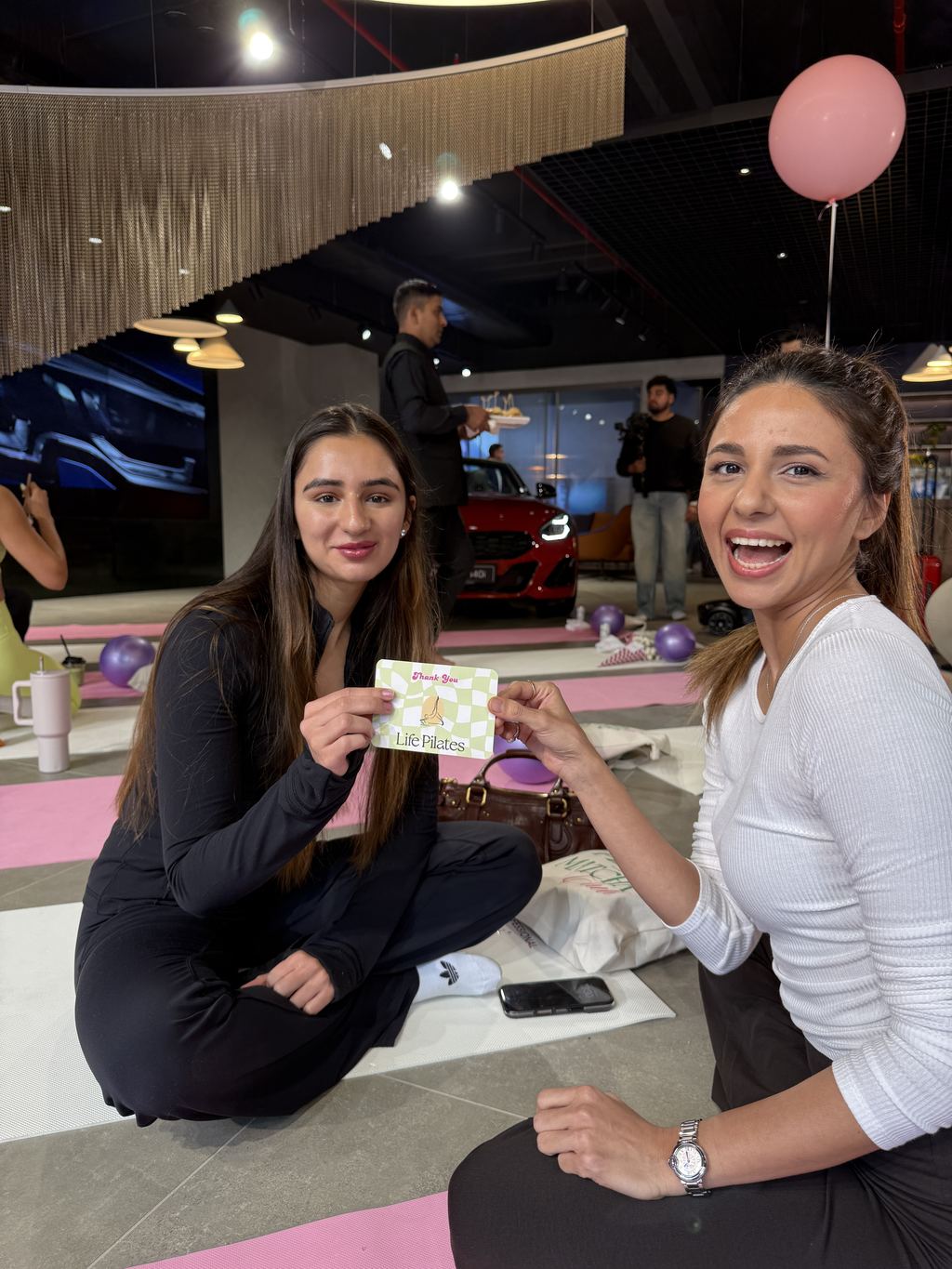 Two guests with Life Pilates thank-you cards at an off-site class