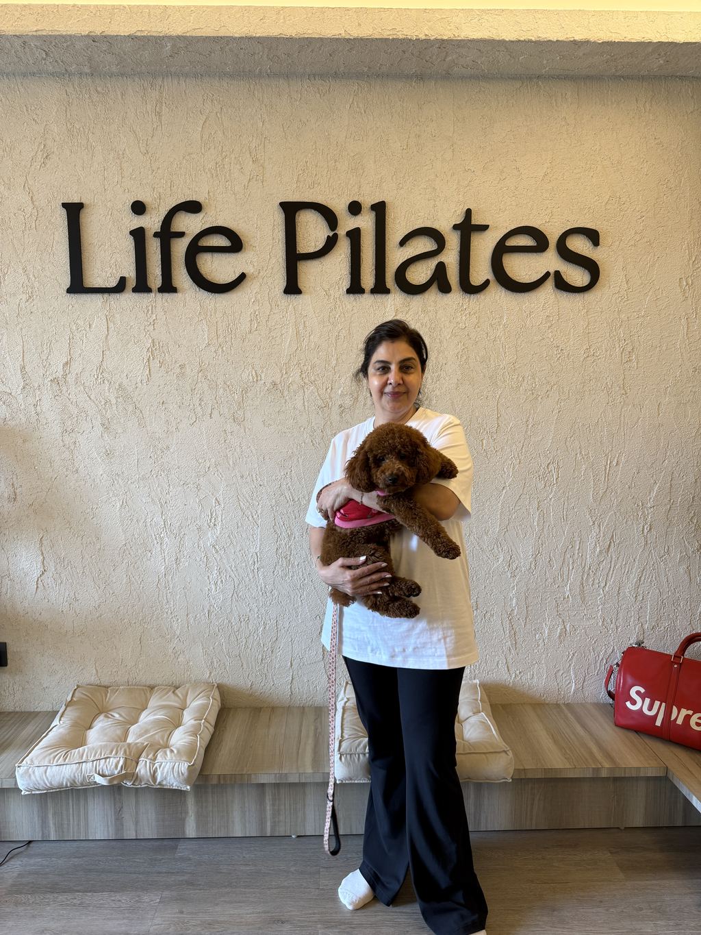 A member with her dog under the Life Pilates wall lettering