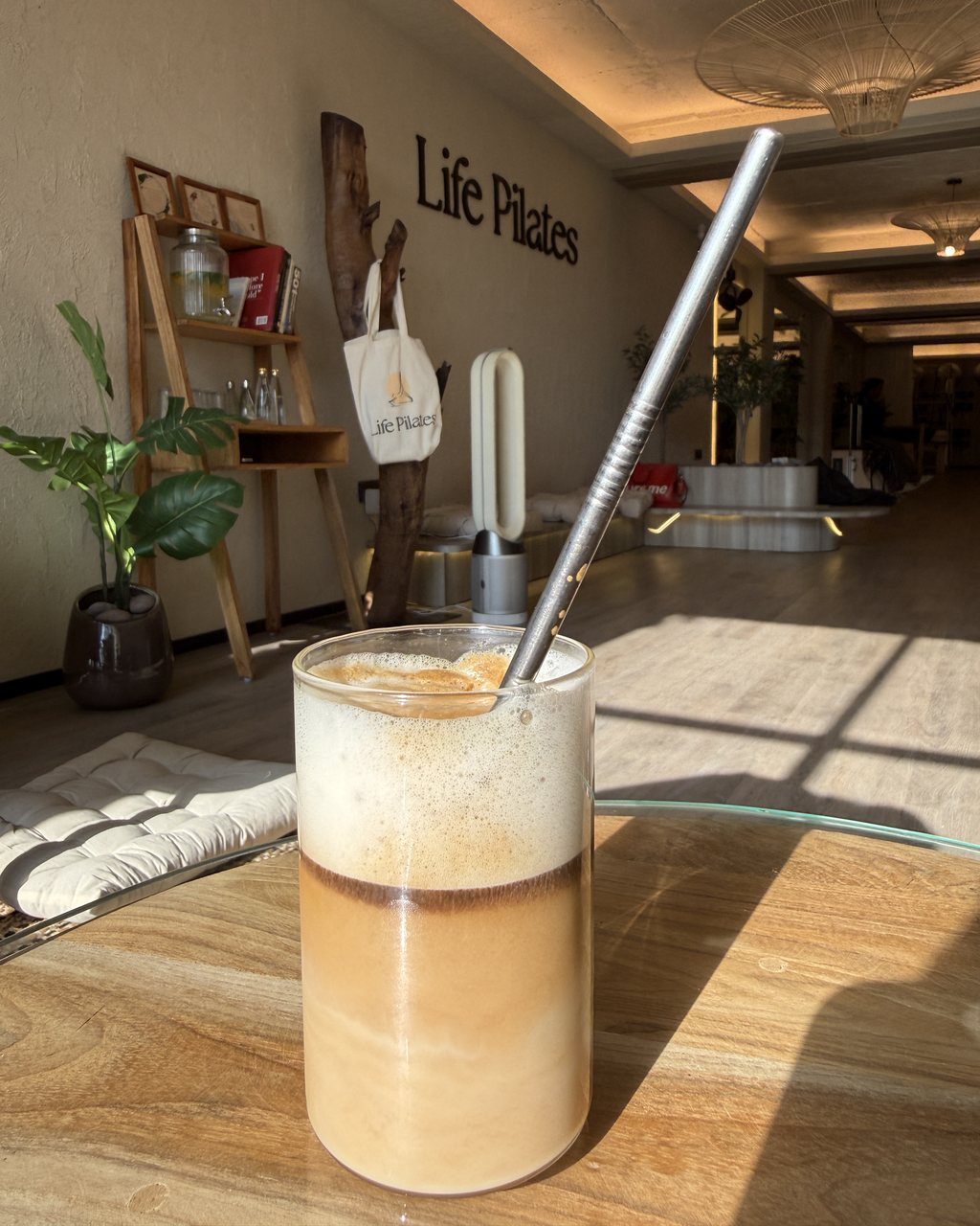 An iced latte on the lounge table, with the Life Pilates wall behind it